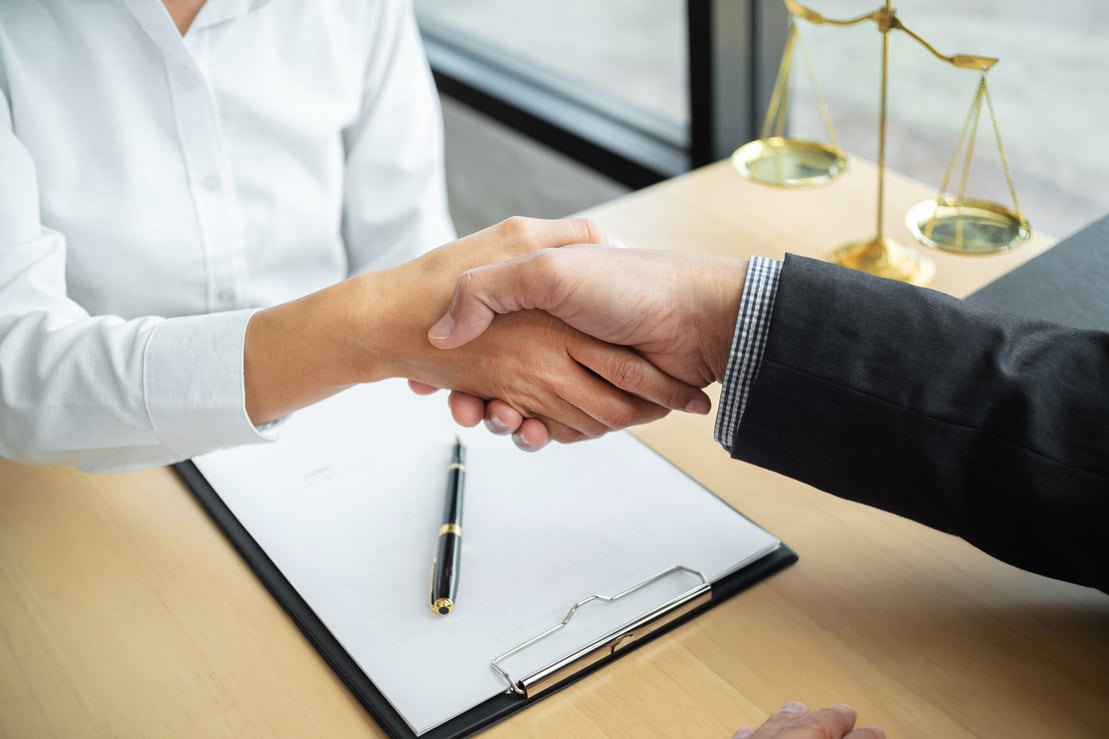 Lawyer consultant shaking hand with client in law firm.